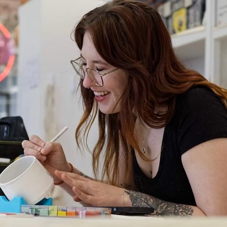 Steph Kubish hand painting a ceramic mug